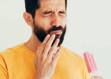 man with popsicle wincing in pain