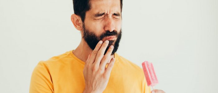 man with popsicle wincing in pain