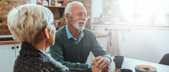 Older couple sitting at table talking 