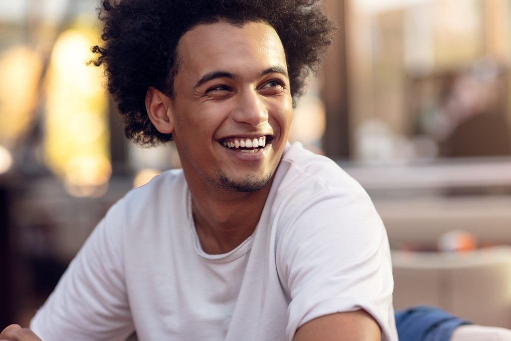 Smiling man in white tshirt sitting outside