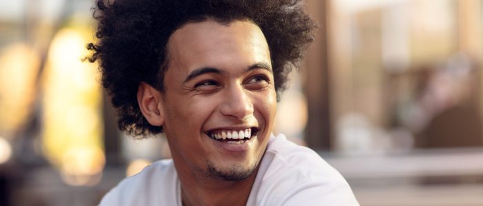 Smiling man in white tshirt sitting outside