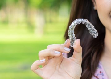 Close Up Young Beautiful Asian Woman Smiling With Hand Holding Clear Aligners