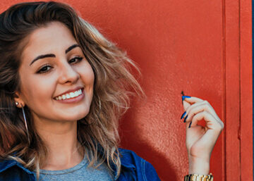 Smiling Woman Standing In Front Of Orange And Blue Background