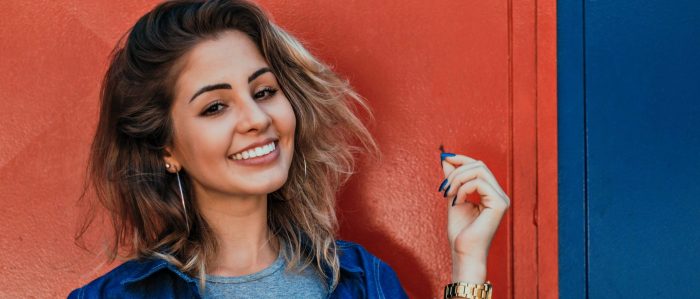 Smiling Woman Standing In Front Of Orange And Blue Background