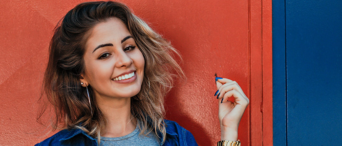 Smiling Woman Standing In Front Of Orange And Blue Background